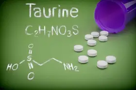 La taurina, un amminoacido essenziale, è rappresentata dalla sua formula chimica e da pillole bianche.