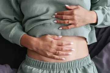 Mani che accarezzano un addome gonfio, forse per colpa del riso rosso fermentato che gonfia la pancia.